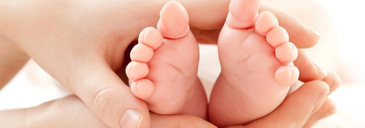 Close‑up of an adult gently holding a baby’s feet