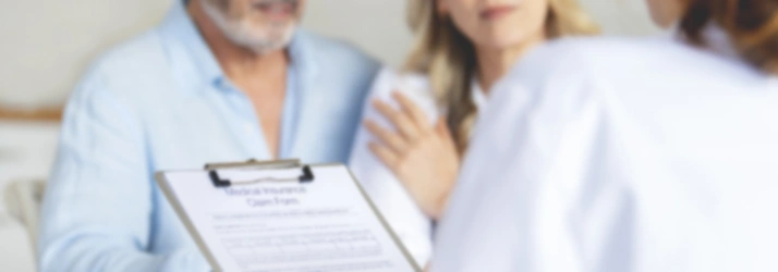 Medical professional holding a clipboard with a form while speaking with two patients