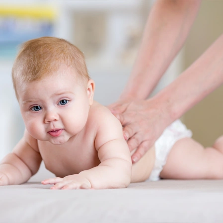An infant lying on their stomach on a soft surface