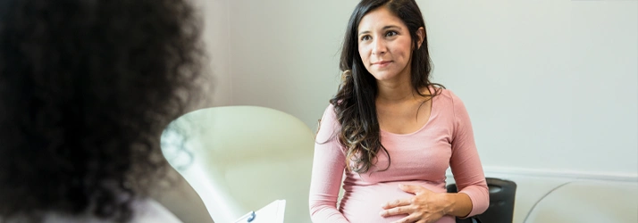 Pregnant person sitting in a chair holding their belly