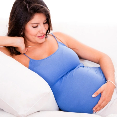 A pregnant person reclining comfortably on a white couch